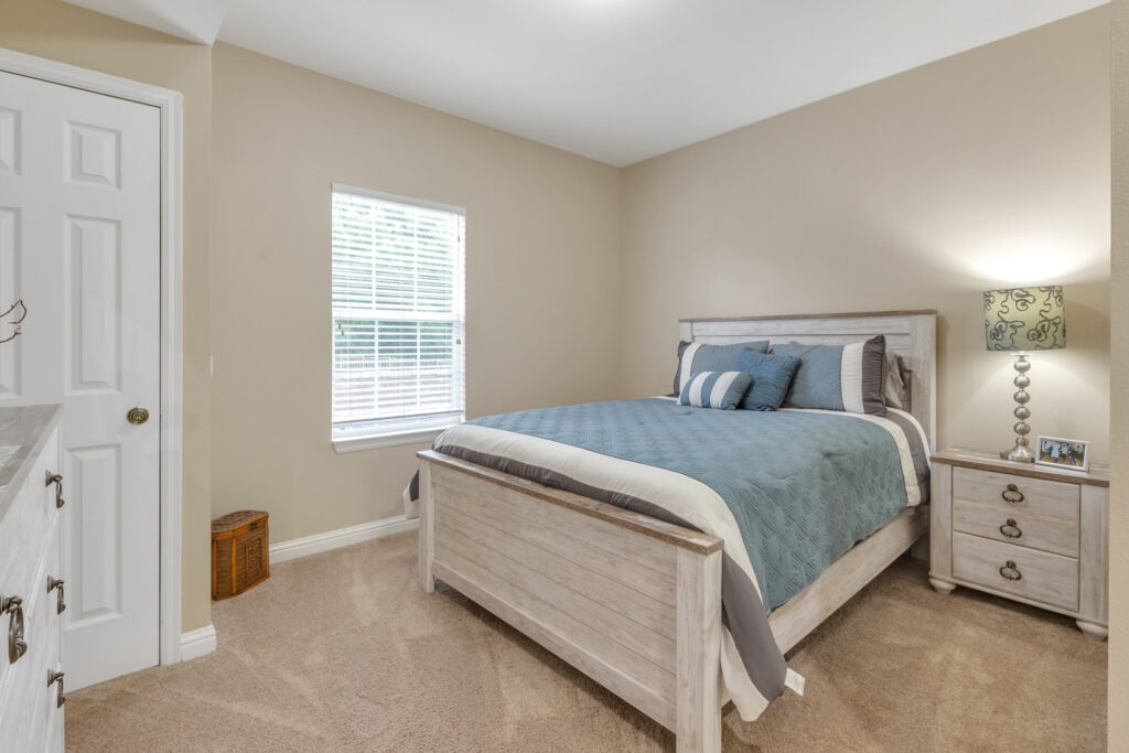 A spacious, well-lit, furnished bedroom at Town Village Tulsa, a senior living community near Glenpool offering independent living and short-term stays.